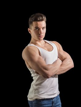 Handsome young muscular man looking at camera, in studio shot over neutral dark background