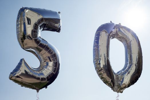 silver balloons for a 50th anniversary floating among the clouds