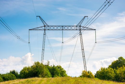 power lines tower on a meadow against the blue sky. lovely energy industry background. efficient electricity delivery concept. beautiful and bright cloudscape