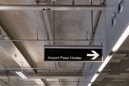 Airport pass holder information board sign with white character on black background at international airport terminal.