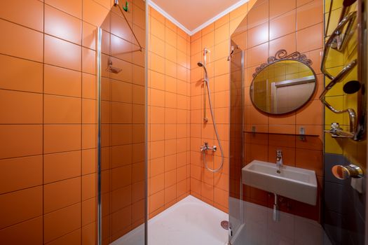 Small orange tile bathroom with Shower cabin and sink