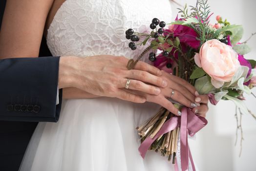 Beautiful wedding bouquet in bride's and groom's hands close up view