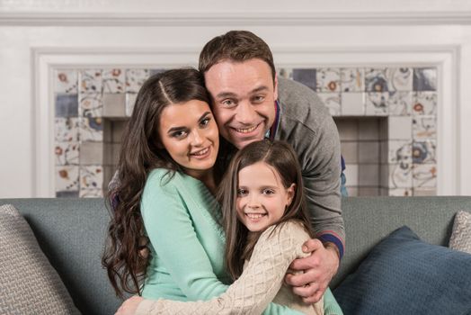 Family portrait of happy parents and their daughter at home