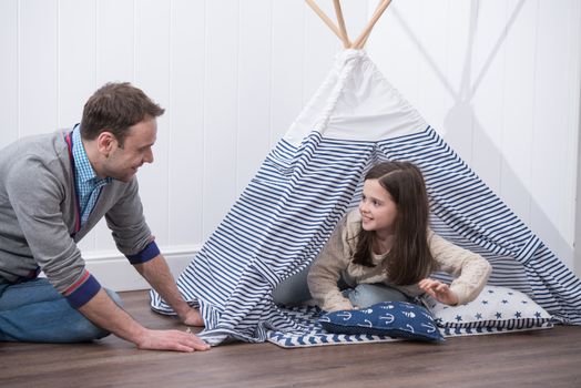 Father and daughter playing at home with constructed wigwam