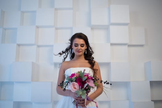 Beautiful bride posing in her wedding day with flower bouquet