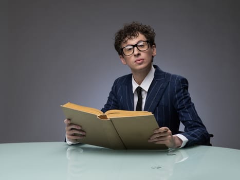 Funny man in striped suit reading a book over gray background. Professional actor facial expression.