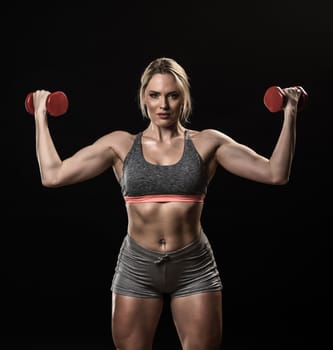 Beautiful muscular woman lifting dumbbells isolated on black background