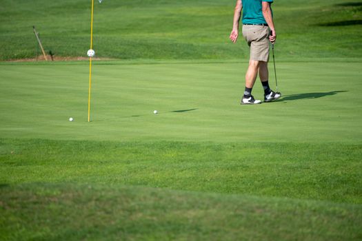 Golfer on the green, mature male putting with several balls, not recognizable, copyspace