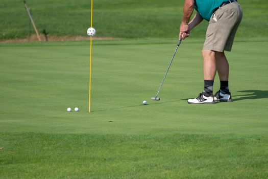 Golfer on the green, mature male putting with several balls, not recognizable, copyspace