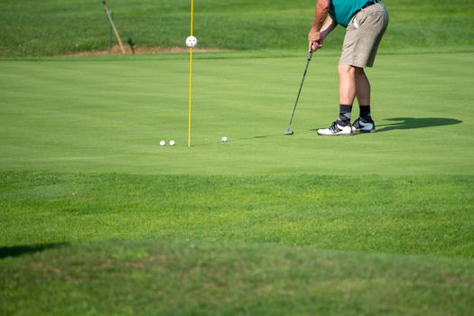 Golfer on the green, mature male putting with several balls, not recognizable, copyspace