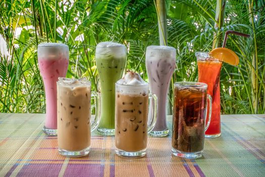 group of iced milk , tea and coffee on table with nature background