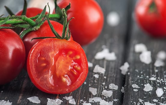 Sliced cherry tomato and salt. Blurred background.