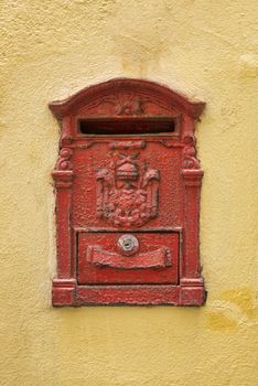 Old red Mailbox  cracked and rusting on yellow wall