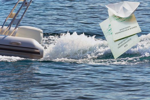 Dinghy with outboard motor and document of the German boat license lake as well as Binnen, inscription in German "Sportbootführerschein Binnen-See"