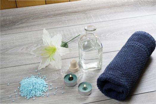 a bottle of massage oil, salts and a towel on the table