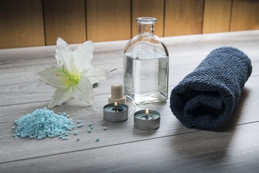 a bottle of massage oil, salts and a towel on the table