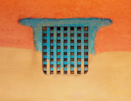 Traditional wooden Nepalese window called Ankhi jhyal. Painted blue on orange and ocher mud wall.