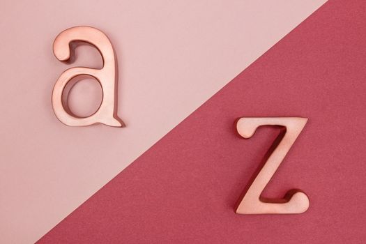 Metal rose gold letters A and Z on pink and cherry red background.