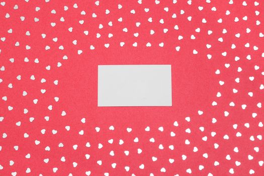 Blank paper card on vibrant pink background with shiny hearts.