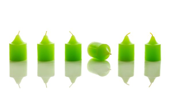 Row of green candles, with one laying down. With reflection, isolated on white background.