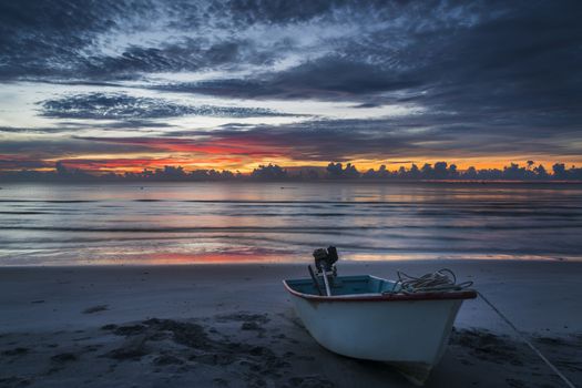 A beautiful tropical dawn with a boat on beach.