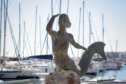 Mermaid stone monument in sailing yachts Mediterranean sea marina