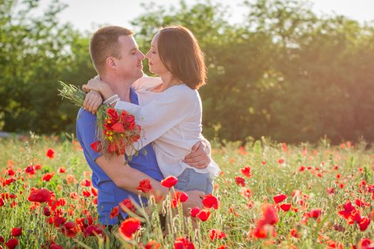 Couple among poppy field embracing and smiling nose-to-nose