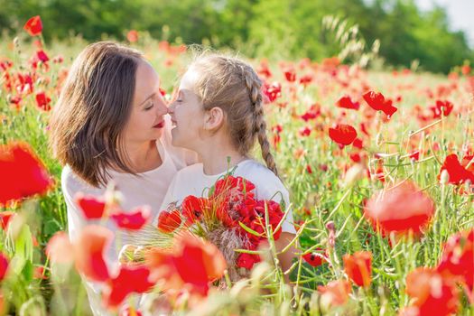 Mother brunette in a white dress with daughter together on blossoming red poppies field