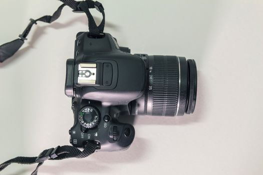 Closeup top view of modern black DSLR camera on white background.