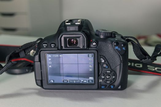 Closeup of modern black DSLR camera on white table.