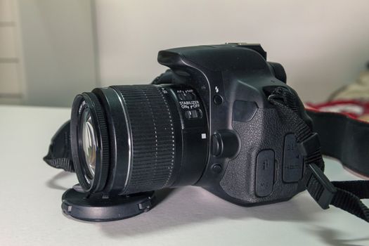 Closeup of modern black DSLR camera on white table.