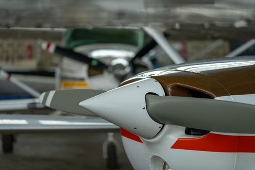 Small Sport Aircraft parked in hangar, close up. detail view of front, nose, cowling and propeller, piston aircraft