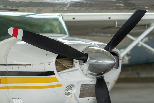 Small Sport Aircraft parked in hangar, close up. detail view of front, nose, cowling and propeller, piston aircraft