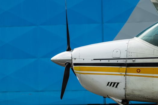 Small Sport Aircraft parked in hangar, close up. detail view of front, nose, cowling and propeller, piston aircraft