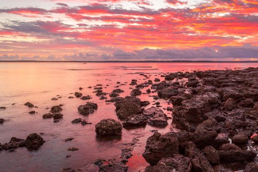 Rich red sunrise from the rockshelf at a small coastal township called Callala Bay a tranquil setting and suitable mooring for boats and yachts too.