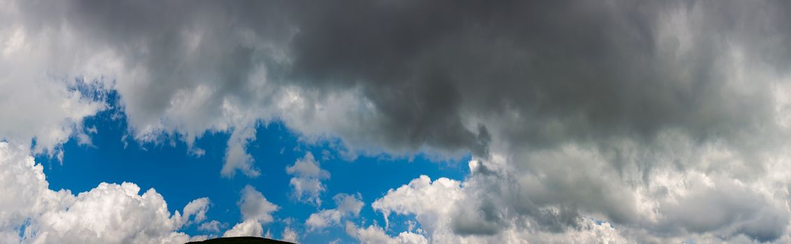 amazing cloud formations on a dark blue sky. beautiful side lit cloudscape panorama in summer