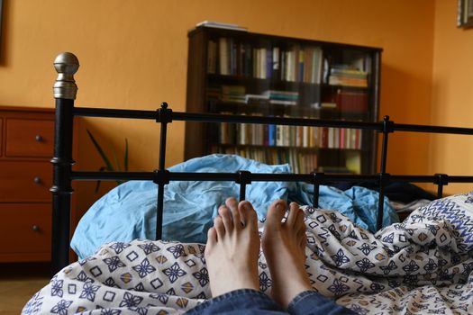 Men feet alone in a bed. Men's feet. Colored background. Close up.