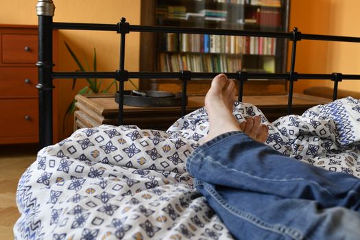 Men feet alone in a bed. Men's feet. Colored background. Close up.