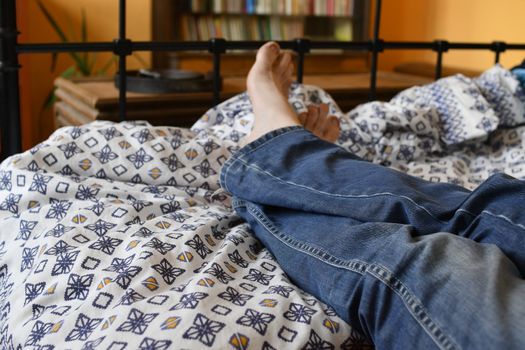 Men feet alone in a bed. Men's feet. Colored background. Close up.