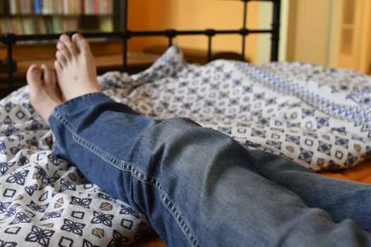 Men feet alone in a bed. Men's feet. Colored background. Close up.