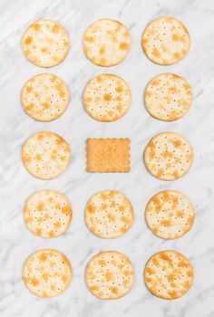 Rows of round crackers and a square tea biscuit in the middle, on marble background.