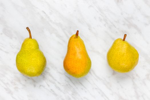 Ripe pears on marble background. Three tasty fruits.