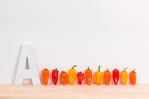 Colorful peppers and letter A on wooden surface. Kitchen decor.