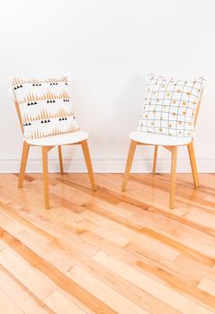 Stylish chairs with ornamental cushions, on hardwood floor. Contemporary home decor.