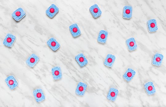 Colorful dishwasher detergent tablets on light gray marble background.