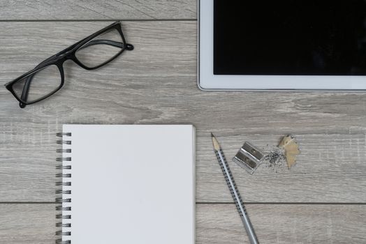 a clipboard, a pair of glasses and a tablet on a wooden table