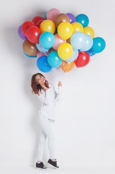 Happy woman with many colorful balloons on white