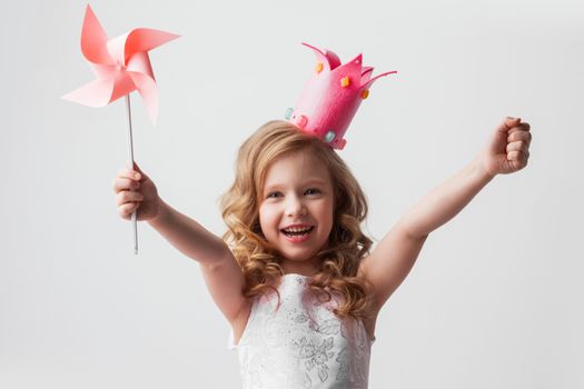 Beautiful little candy princess girl in crown holding pinwheel and smiling