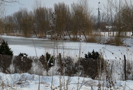 winter landscape with frozen canal and snow all around