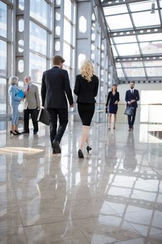 Business people walking in modern glass office corridor